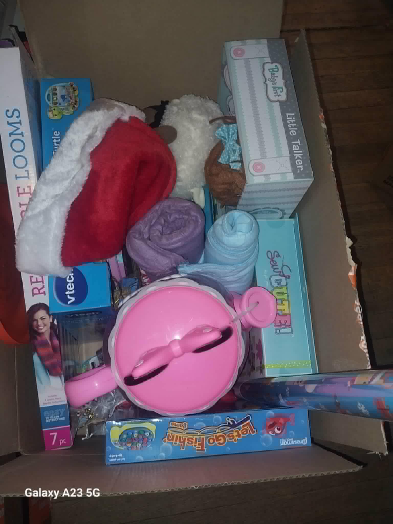 A box of Christmas toys and gifts with a Santa hat for the Community Porch Christmas program in Hoosick Falls NY
