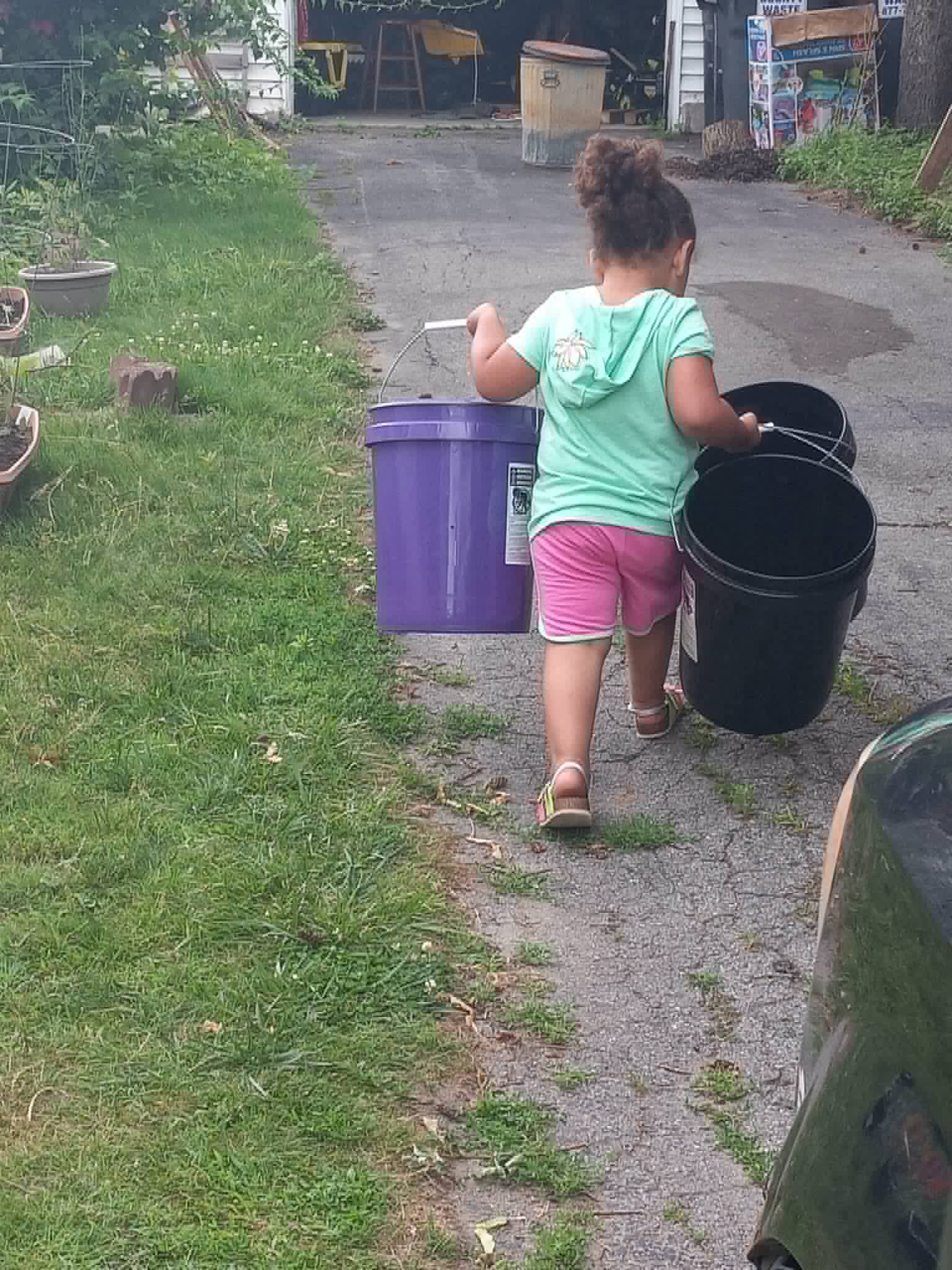 A child carrying garden buckets to help at the Community Porch in Hoosick Falls NY
