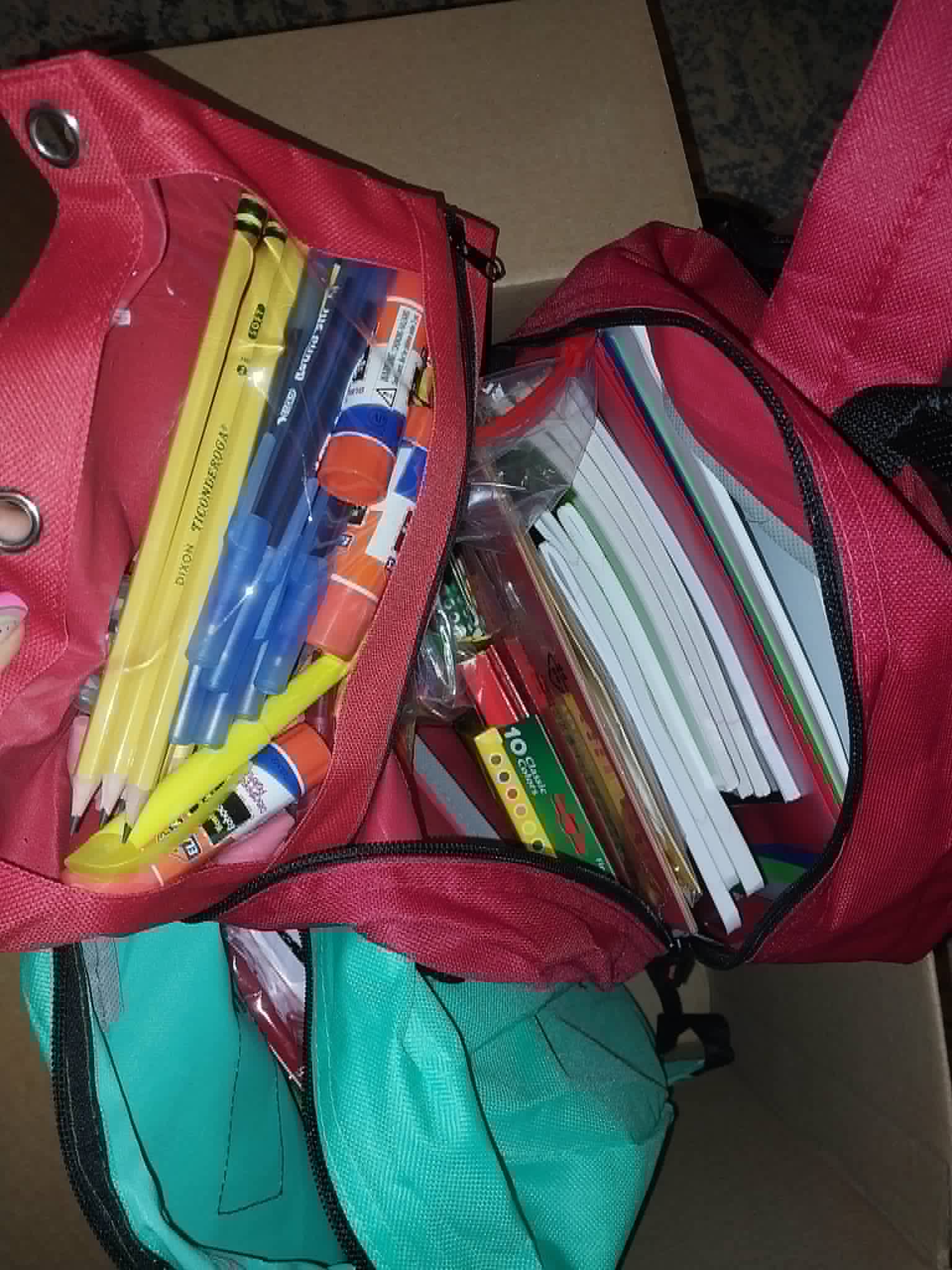 A red backpack packed with pencils, crayons, and notebooks for the Community Porch backpack program in Hoosick Falls NY